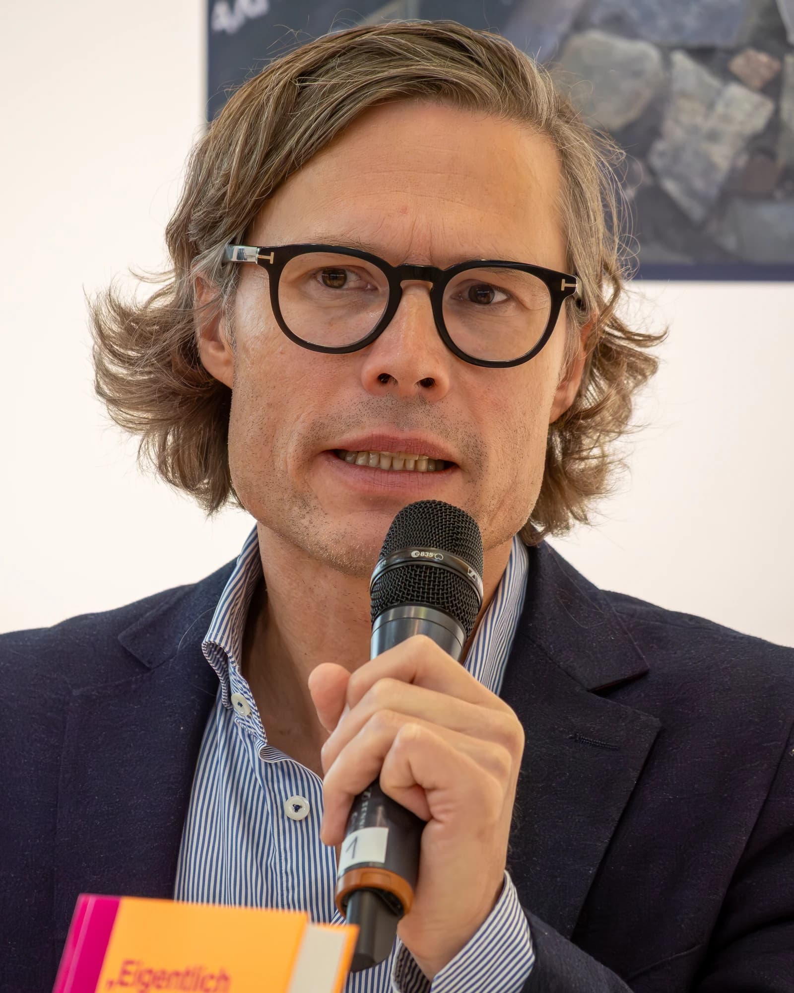 Timo Frasch speaking into a microphone at an event.