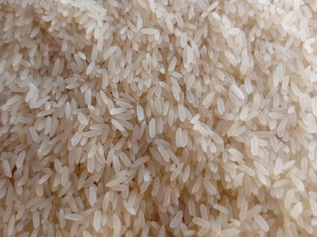 Close-up of numerous white rice grains, illustrating a commodity.