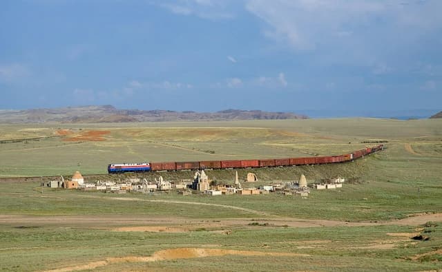 KTZ TE33A Joloman locomotive pulls a long line of freight cars through the Kazakh landscape.