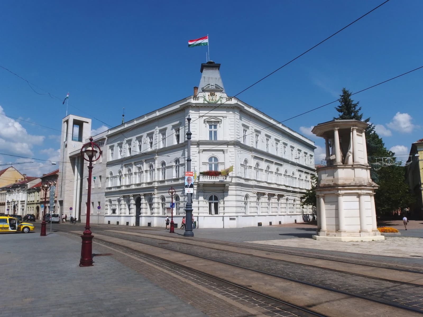 Miskolc City Hall, a white building with an ornate roof, under a clear sky.