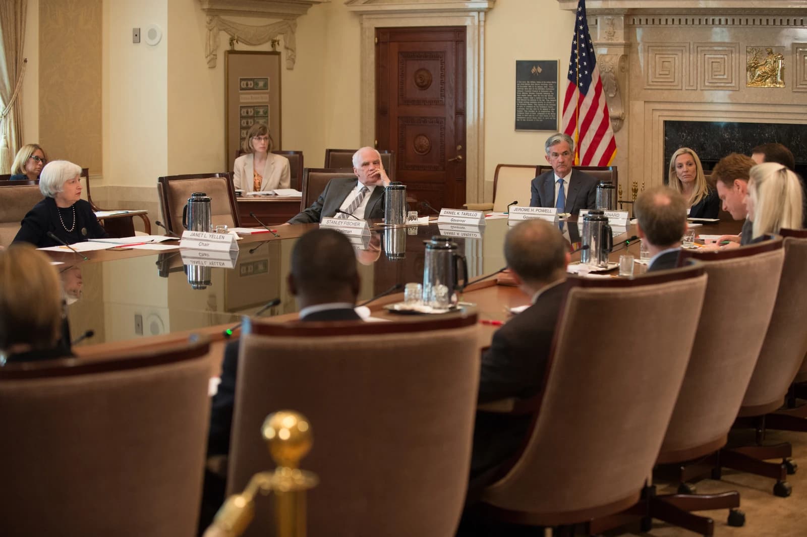 Janet Yellen, Stanley Fischer, and Jerome Powell sitting at a conference table with others.