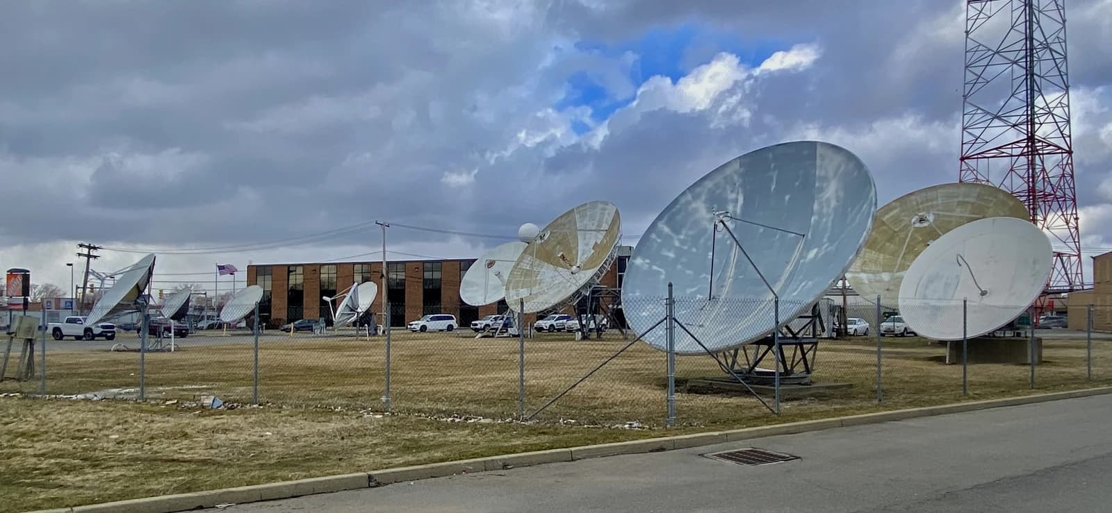 A collection of large satellite dishes in a field outside television studios.