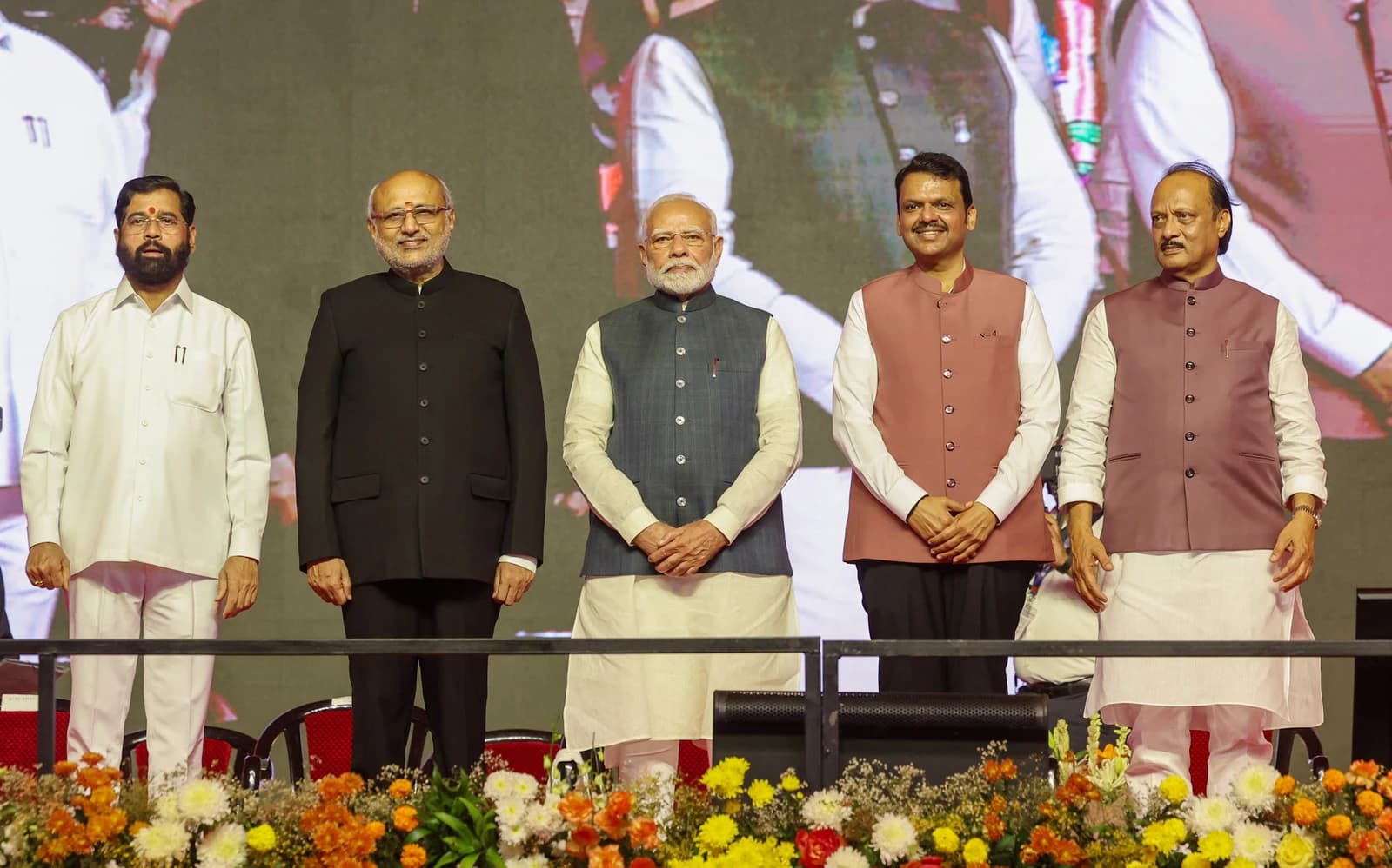 Prime Minister Narendra Modi, Eknath Shinde, and other dignitaries stand on a stage.