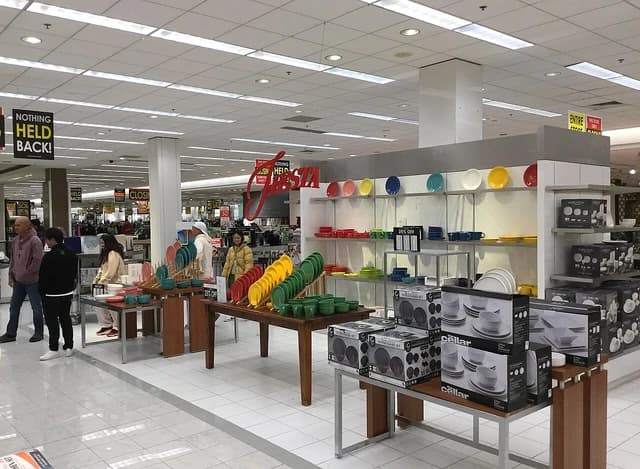 Shoppers browse a colorful display of Fiestaware dishes inside a Macy's department store.
