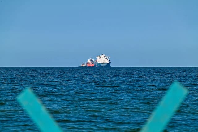 LNG tanker being assisted by a tugboat in the open sea.