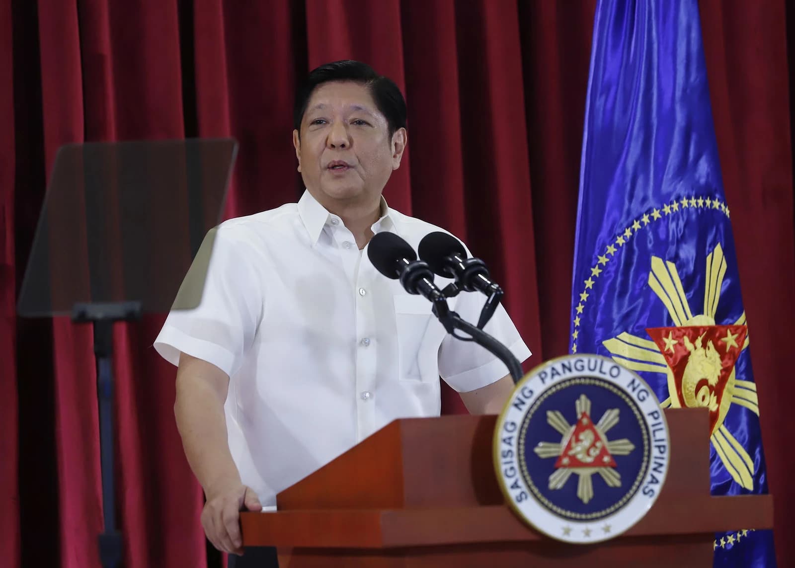 Ferdinand Marcos Jr., President of the Philippines, speaking at a podium with flags.