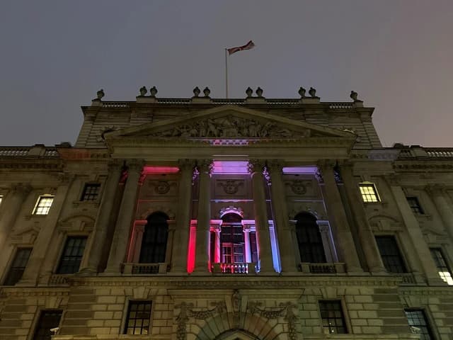 HM Revenue and Customs building, with pillars and a flag, lit at night.