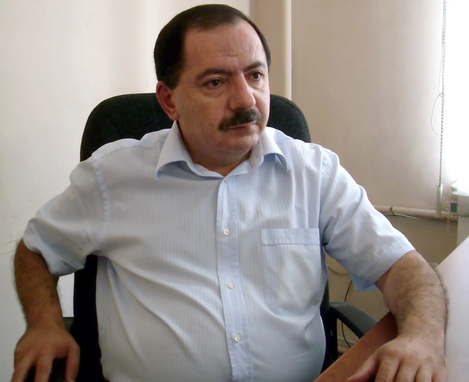 Aghvan Vardanyan, a man with a mustache, seated at a desk indoors.