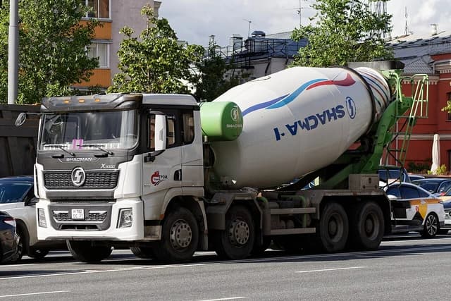 White and green Shacman X3000 concrete mixer truck on a city street in Moscow.