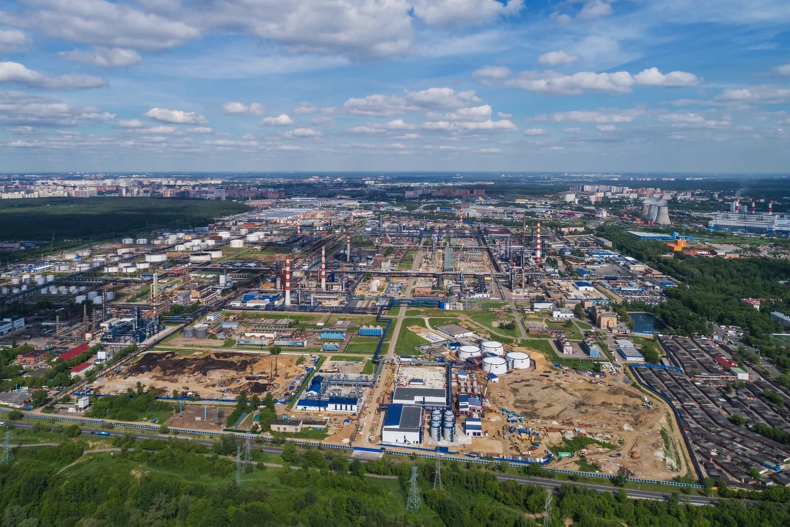 An aerial view shows a sprawling oil refinery complex under a partly cloudy sky.