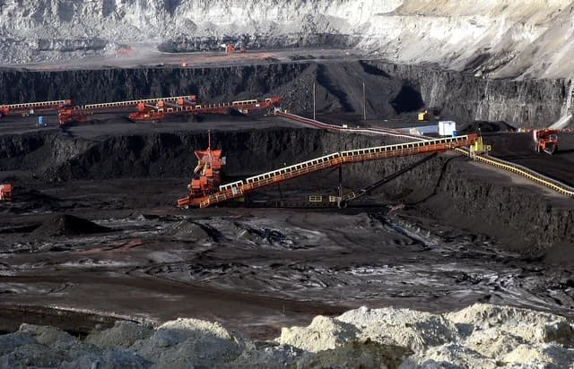 Surface coal mine with heavy machinery and conveyor systems moving coal in Gillette, Wyoming.