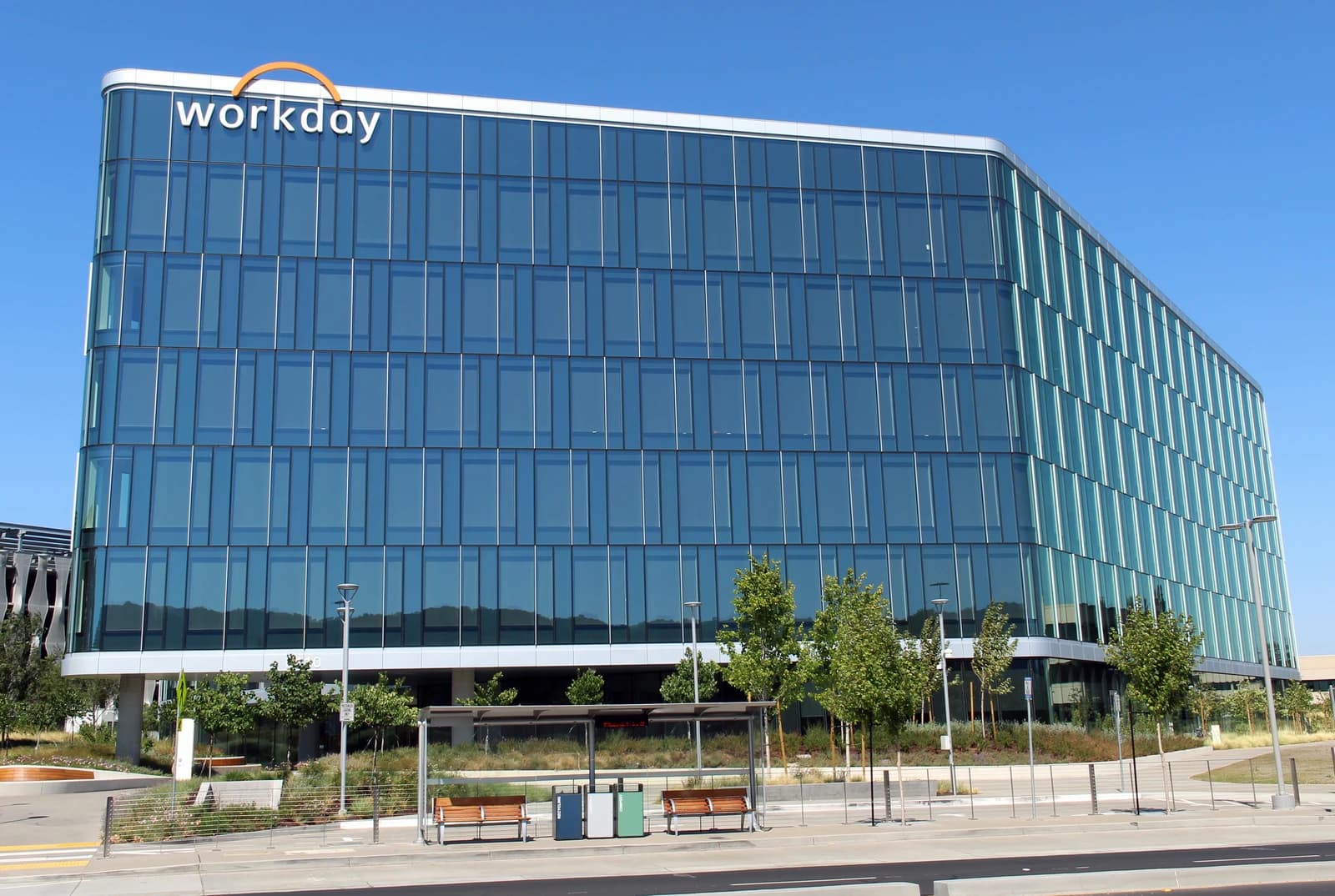 Modern glass building with 'Workday' logo on top, against a clear blue sky.