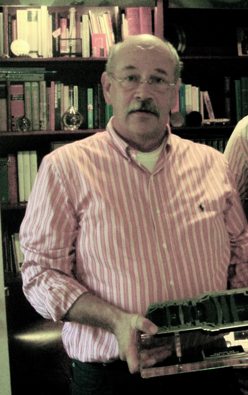 Ton Willekens holds a lens from ASML, standing in front of a bookshelf.