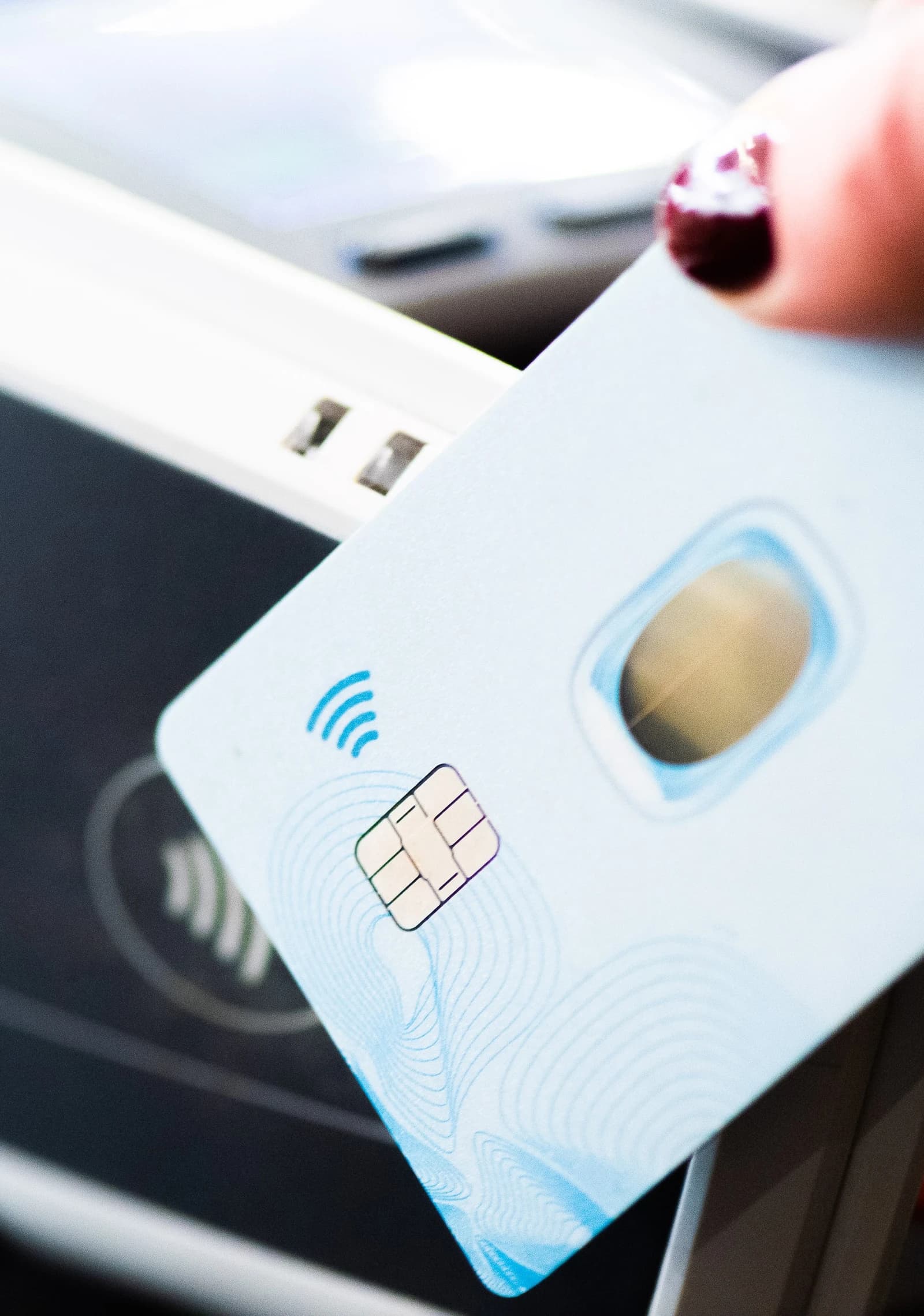 Close-up of a person holding a light blue payment card with a chip.