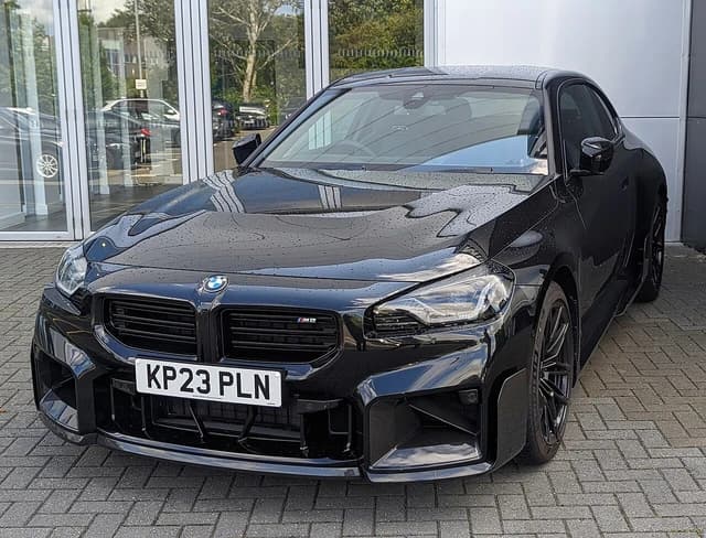 2023 black BMW M2 sports coupe parked on a paved surface.