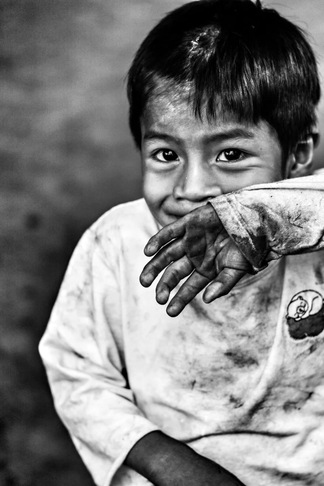 An indigenous child in Tekoa Pyau Village, Brazil, partially covers their face with a hand.