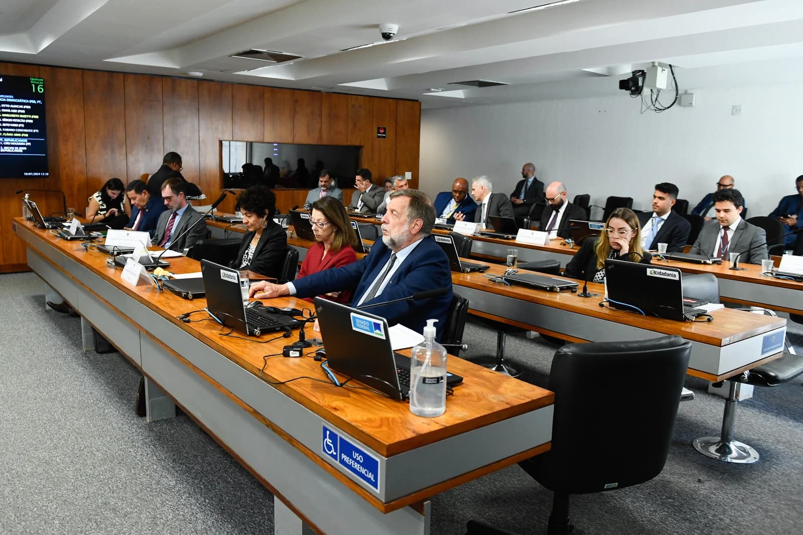 Members of the Brazilian Senate and staff seated at desks in a meeting room.