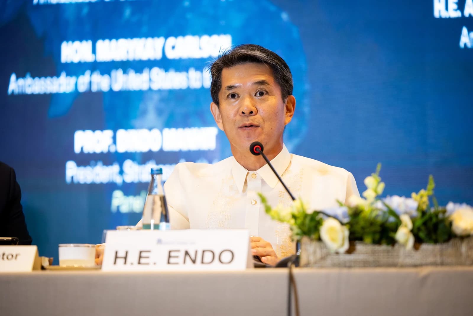 Man speaking into a microphone at a diplomatic roundtable event.