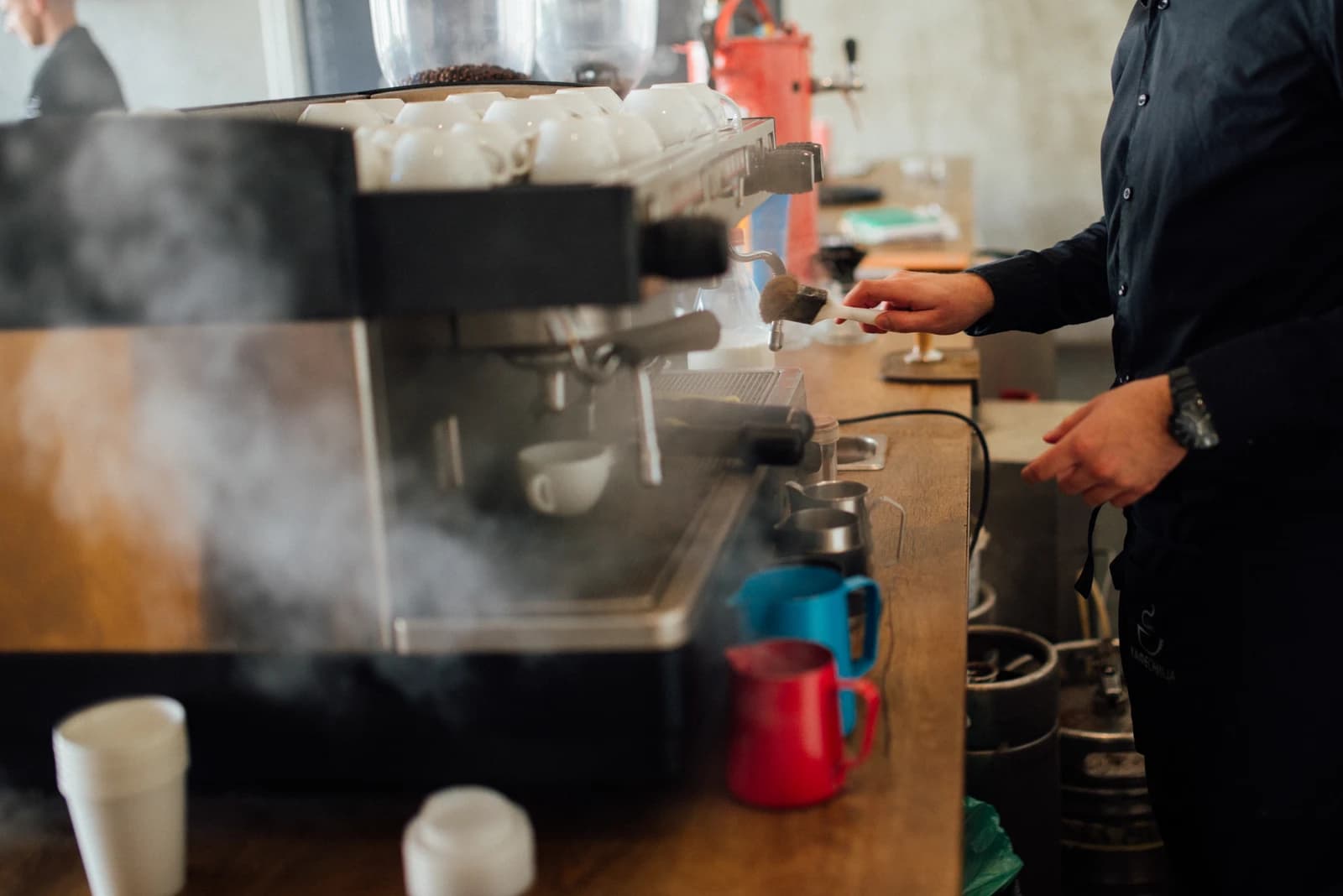 Skilled barista operating steaming espresso equipment in a modern cafe.
