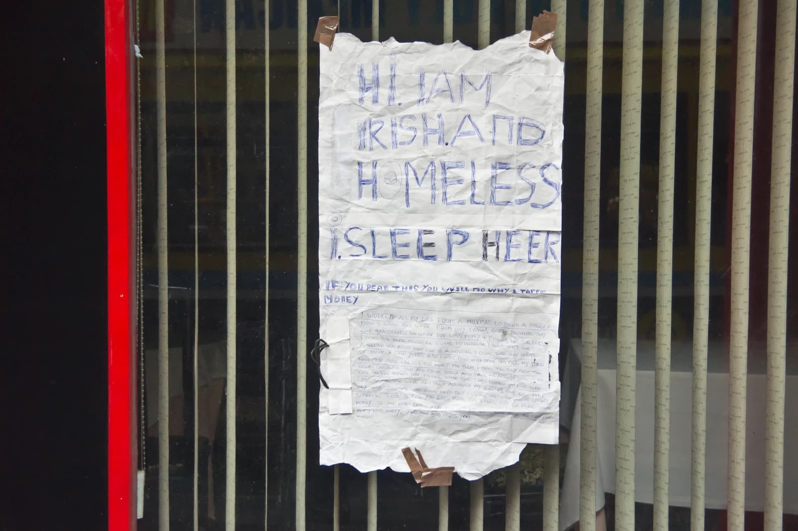 Handwritten sign from an Irish homeless person attached to a metal gate.