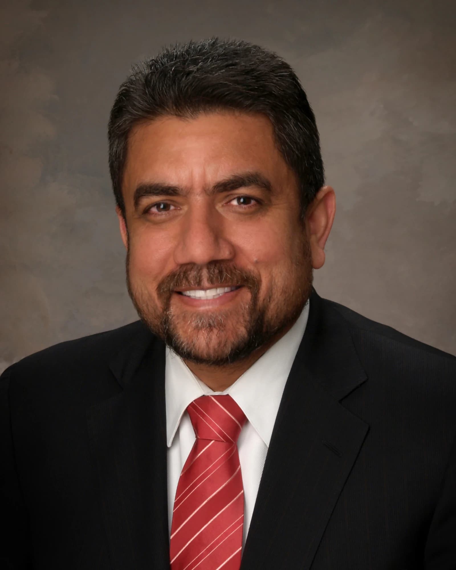Sukh Dhaliwal, former Liberal MP, looks directly at the camera and smiles.