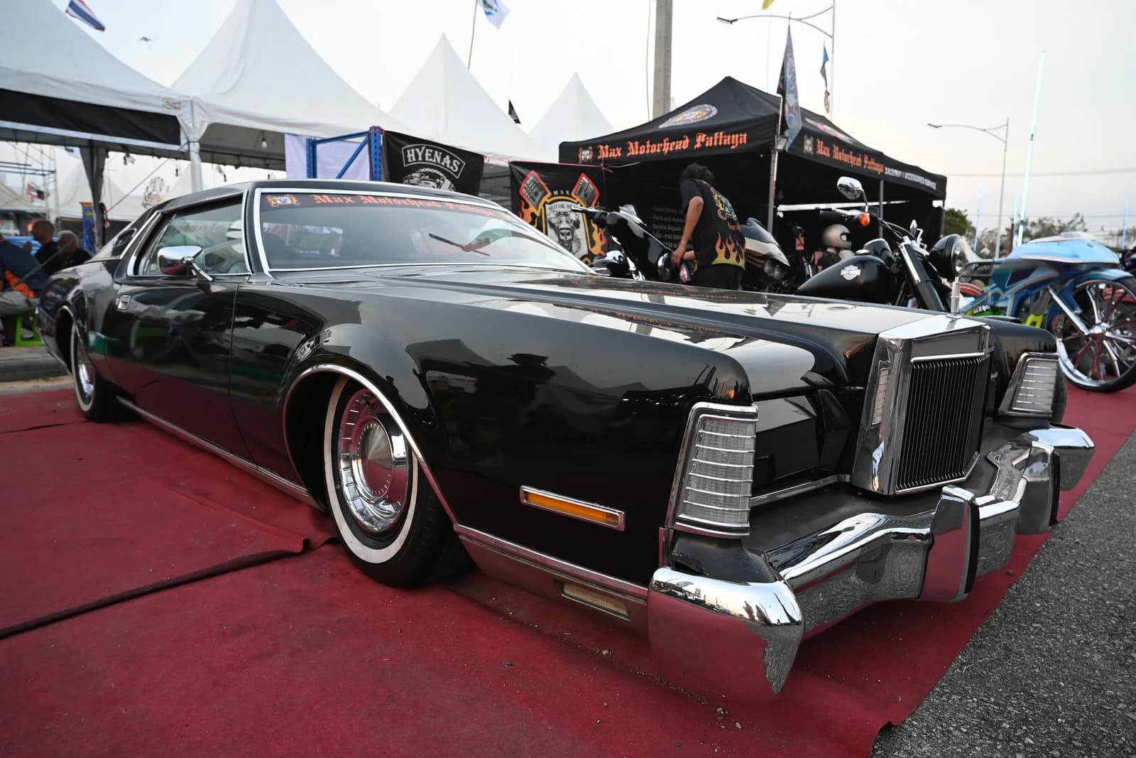 Sleek black classic lowrider with gleaming chrome on display at a car show.