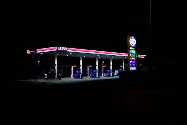 Empty Esso gas station at night showing a price display and pumps.