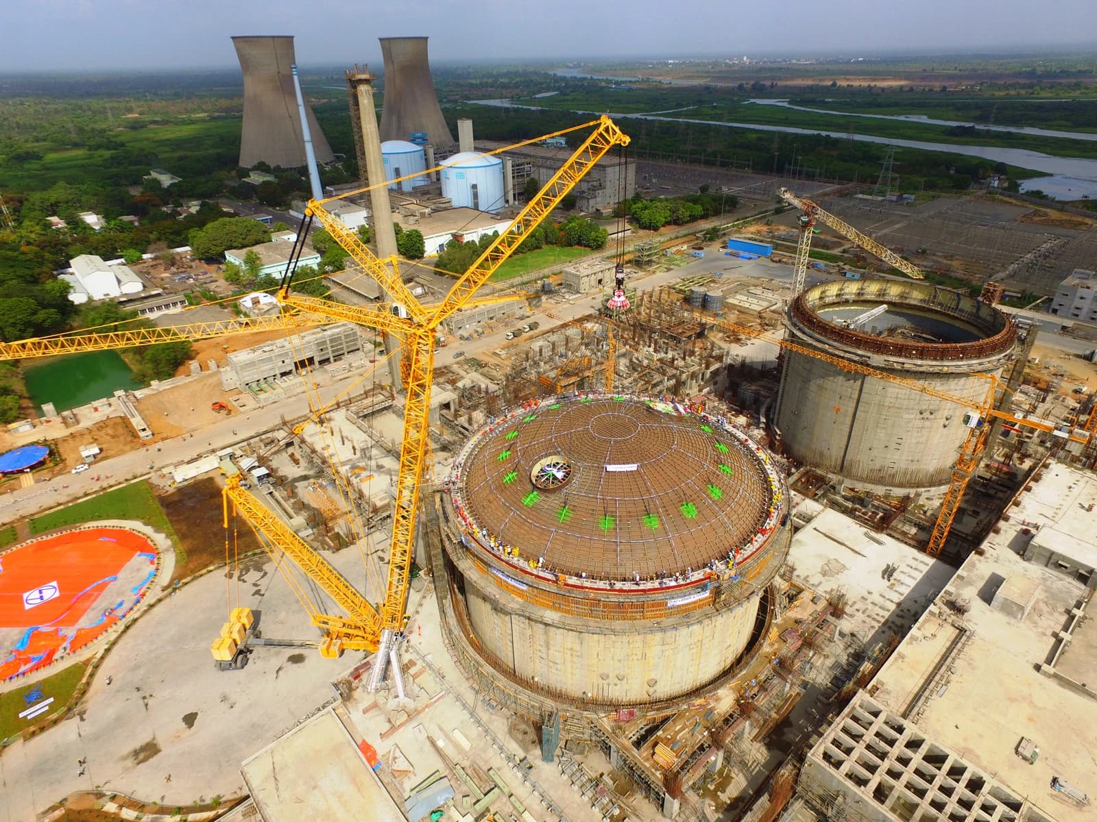 Aerial view of a nuclear power plant construction site with large reactor domes.