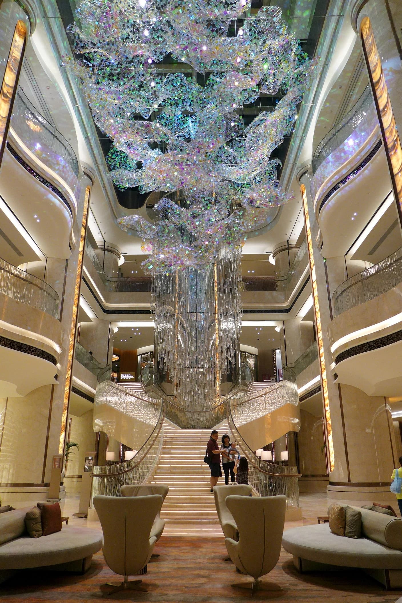 Lobby of the JW Marriott Hotel with a large ornate chandelier and curved staircase.
