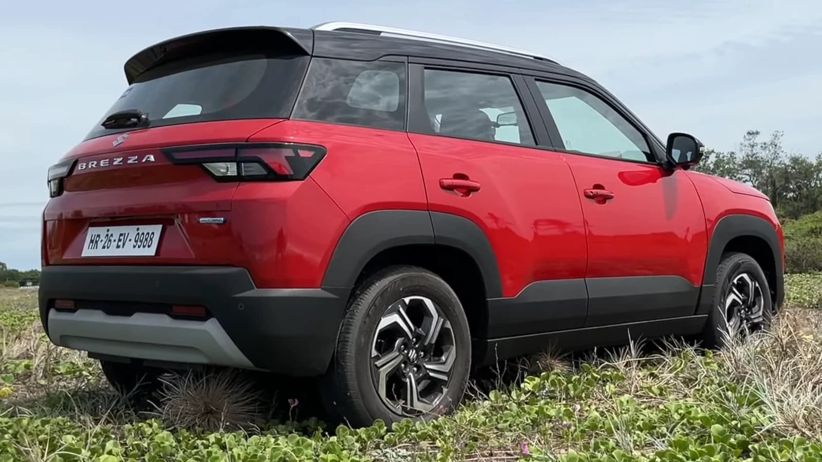 Red 2022 Maruti Suzuki Brezza ZXi+ car, rear quarter view, parked outdoors.