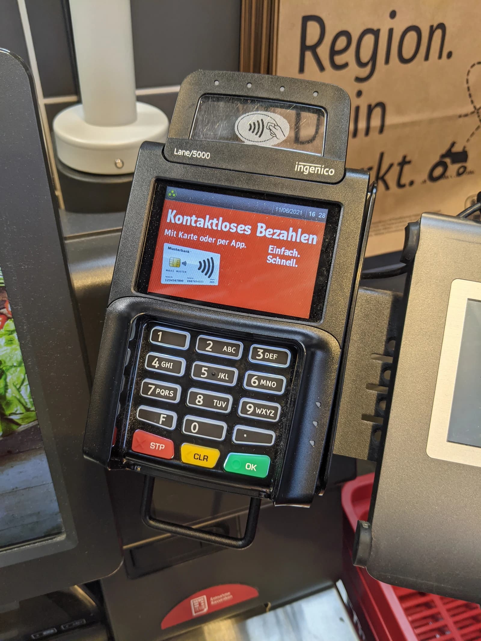 Payment terminal at a self-checkout machine displaying contactless payment instructions.