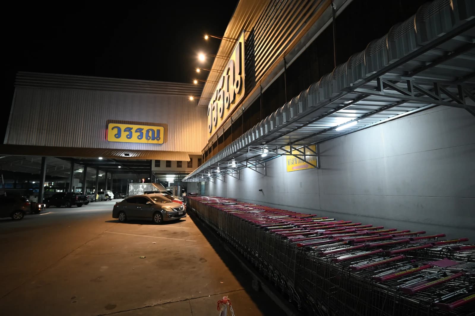 Empty shopping carts lined up outside a supermarket in the evening.