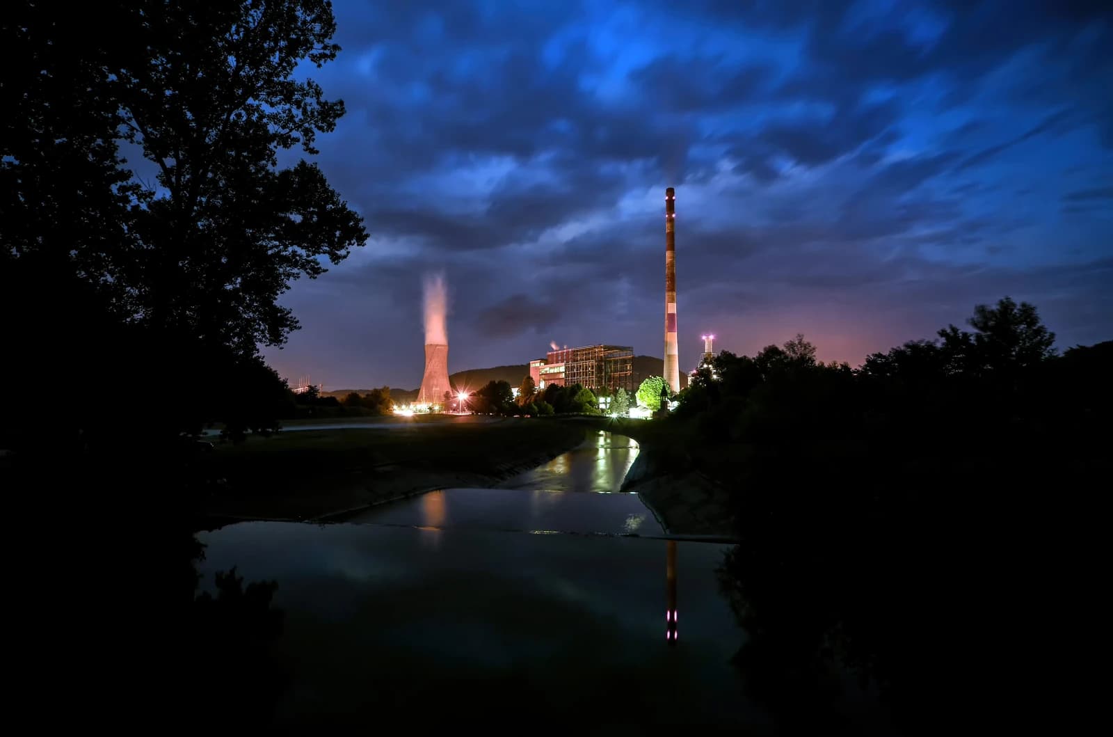 Termoelektrana Ugljevik power plant at night, showing a steaming cooling tower and tall smokestack.