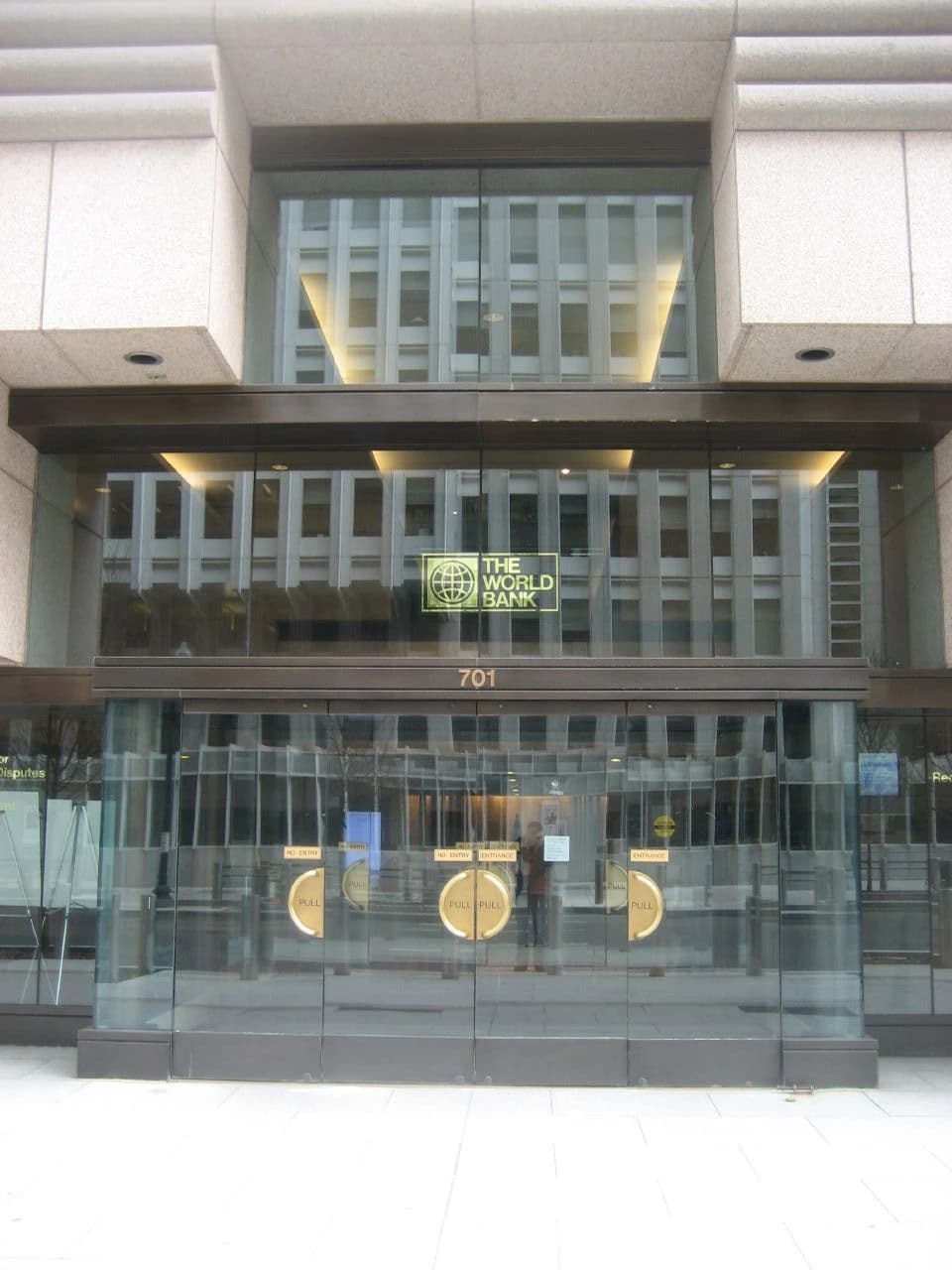 Entrance to the World Bank building with glass doors and the organization's logo above.