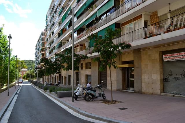 Street view of apartment buildings with balconies and green awnings in Barcelona.