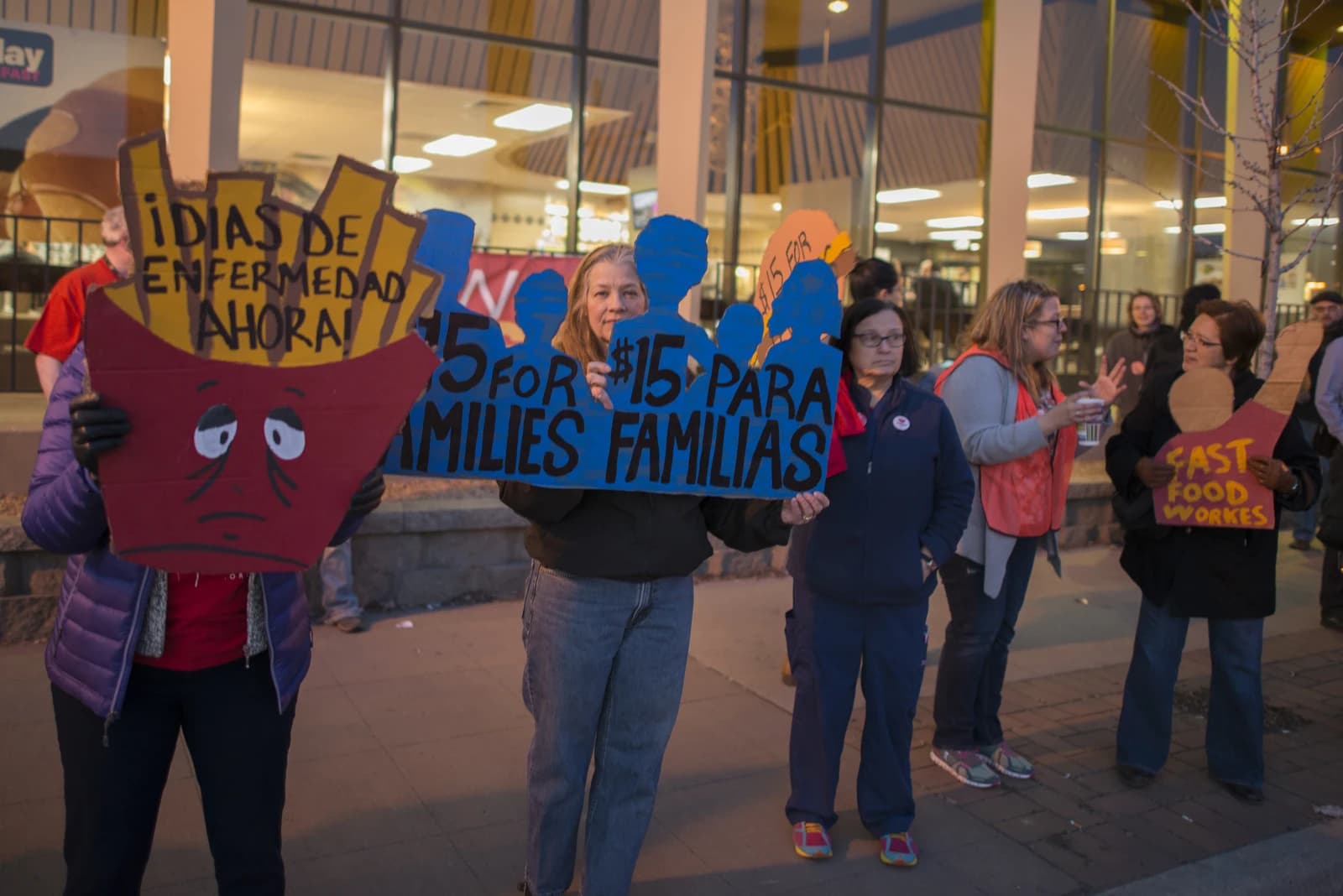 Fast food workers on strike holding signs for higher minimum wage and better benefits.