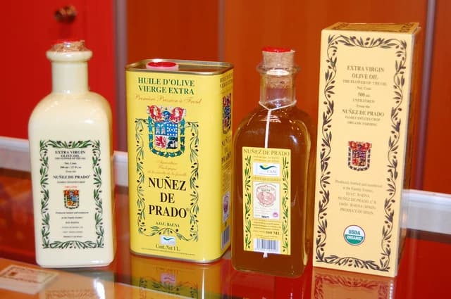 Bottles and a tin of Nuñez de Prado extra virgin olive oil displayed on a surface.