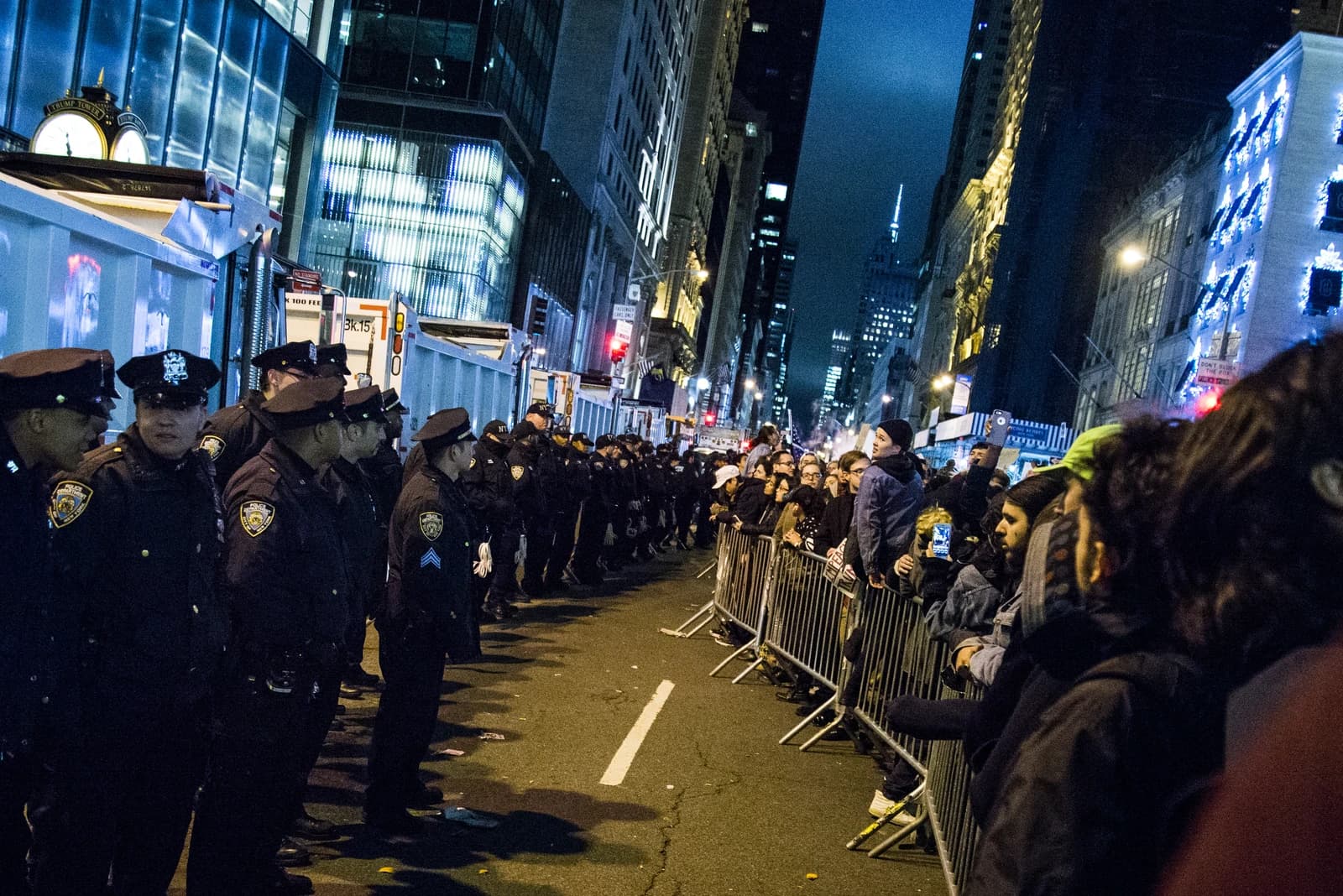 Police officers lined up in front of a metal barrier separating them from demonstrators.