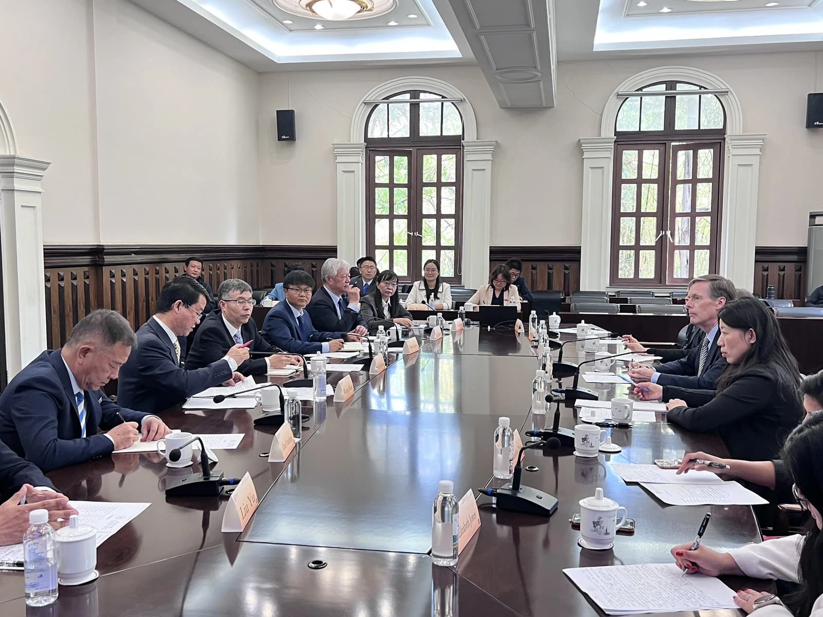US and Chinese university delegations seated at a long conference table during a meeting.