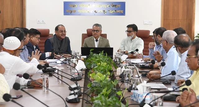 Sheikh Rabiul Alam, flanked by other officials, sits at a conference table during a meeting.