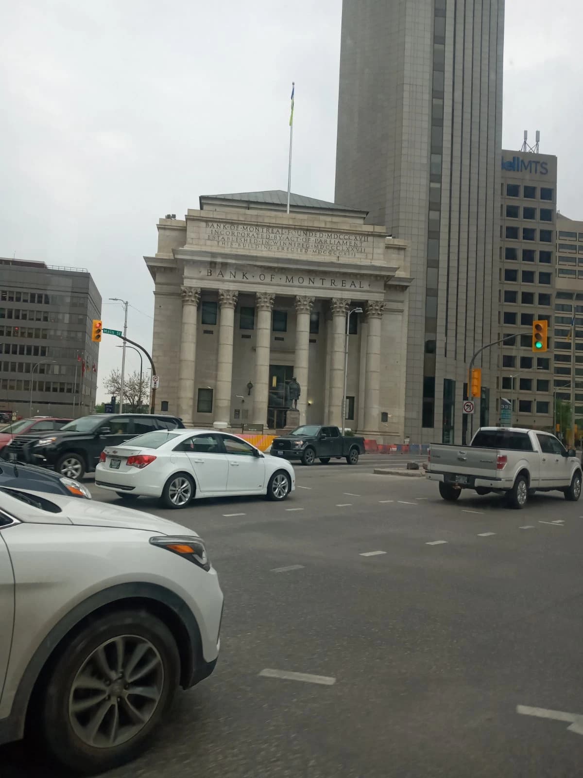 Exterior of the Bank of Montreal building on a street with cars in Winnipeg.
