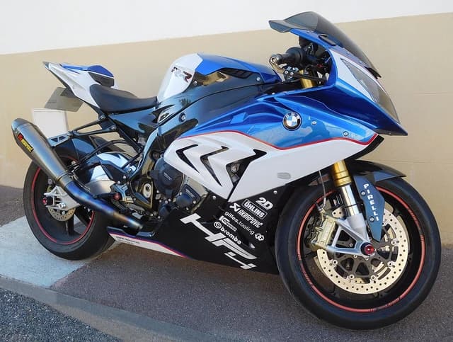 BMW S 1000 RR HP4 motorcycle, blue and white, parked on pavement next to a building.