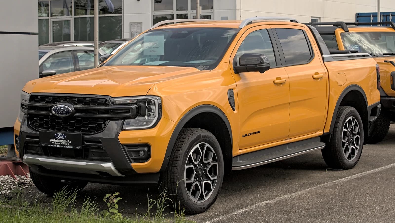 An orange Ford Ranger Wildtrak pickup truck parked at a dealership.