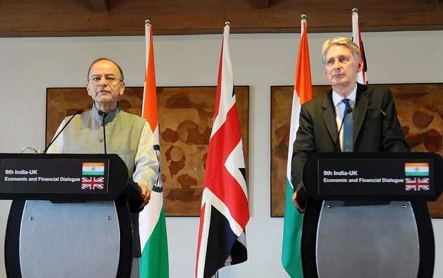 Arun Jaitley and Philip Hammond standing at podiums during a joint press conference.