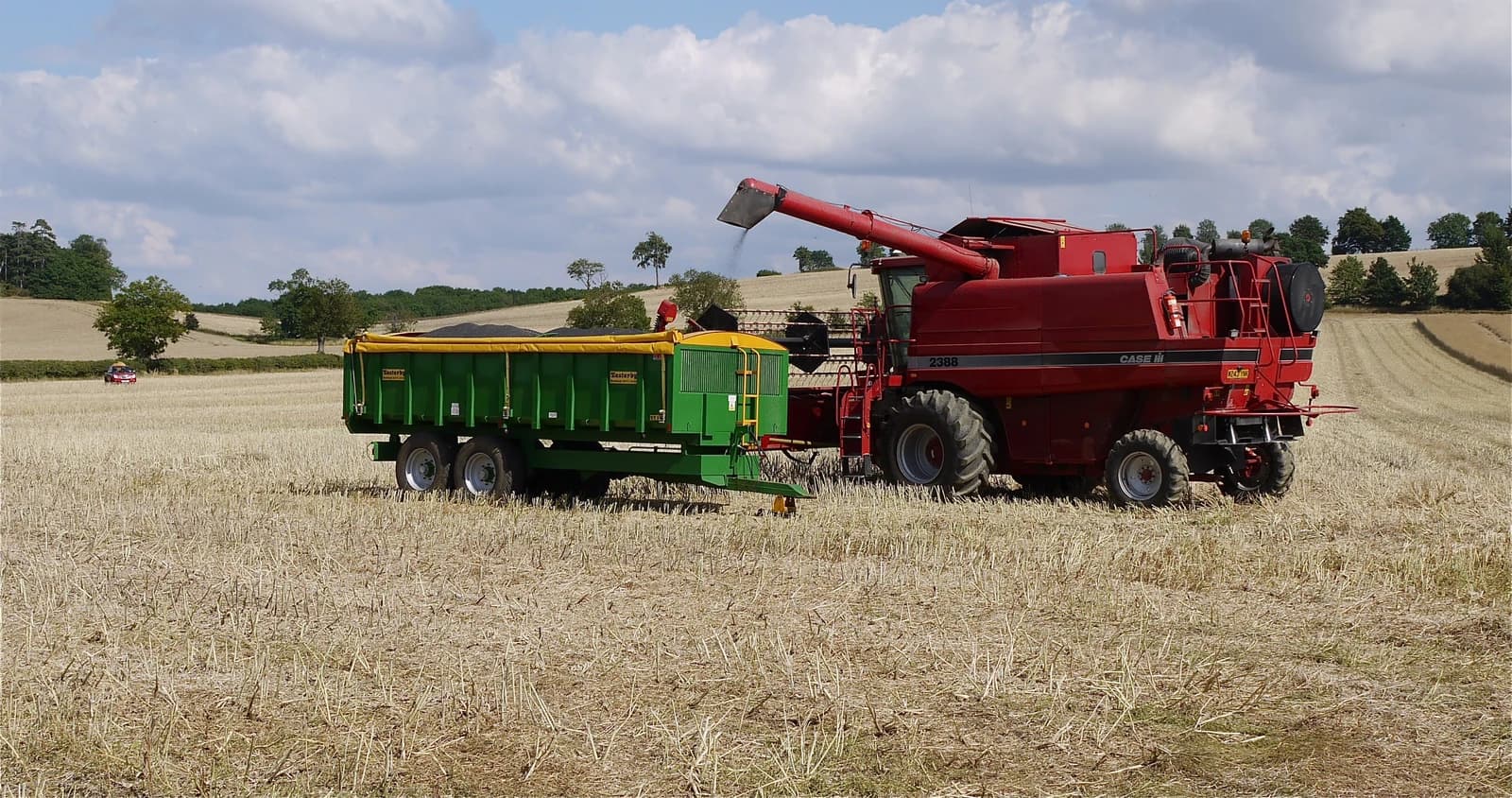 Case IH combine harvester loading rapeseed into an Easterby trailer in a field.