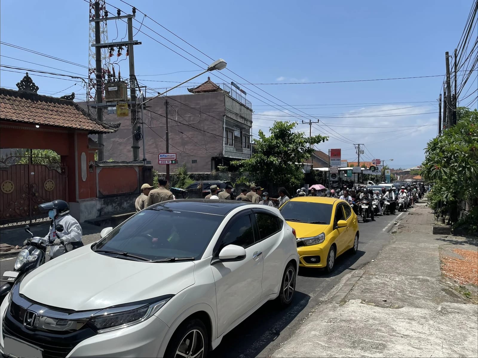 People distributing water bottles to residents queuing for fuel in Klungkung Regency, Bali.