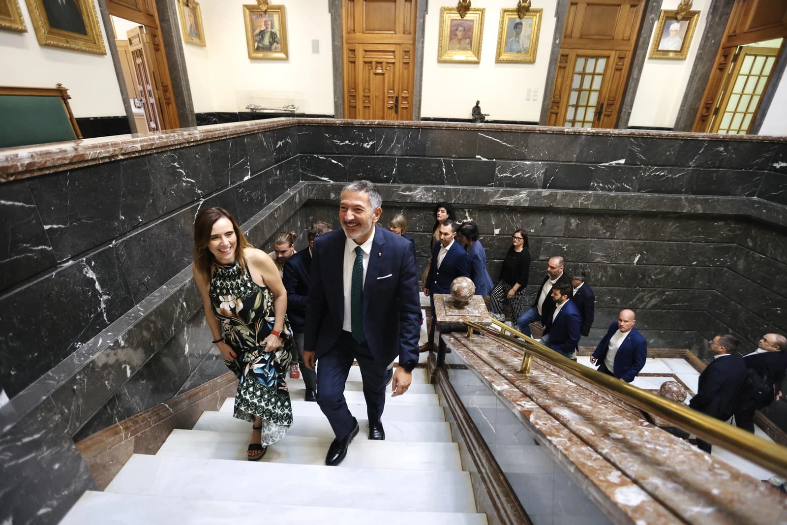 A councilor and other officials walk down a marble staircase in Reus City Hall.