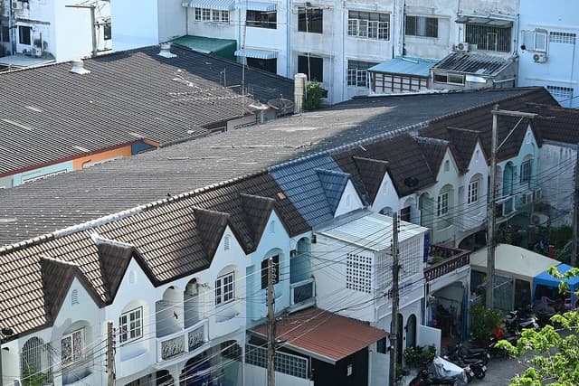 Row of connected townhouses with peaked roofs and balconies on a quiet street.
