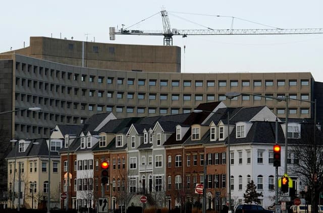 Row of diverse townhouses in Southwest Washington D.C. with a large building and crane behind them.