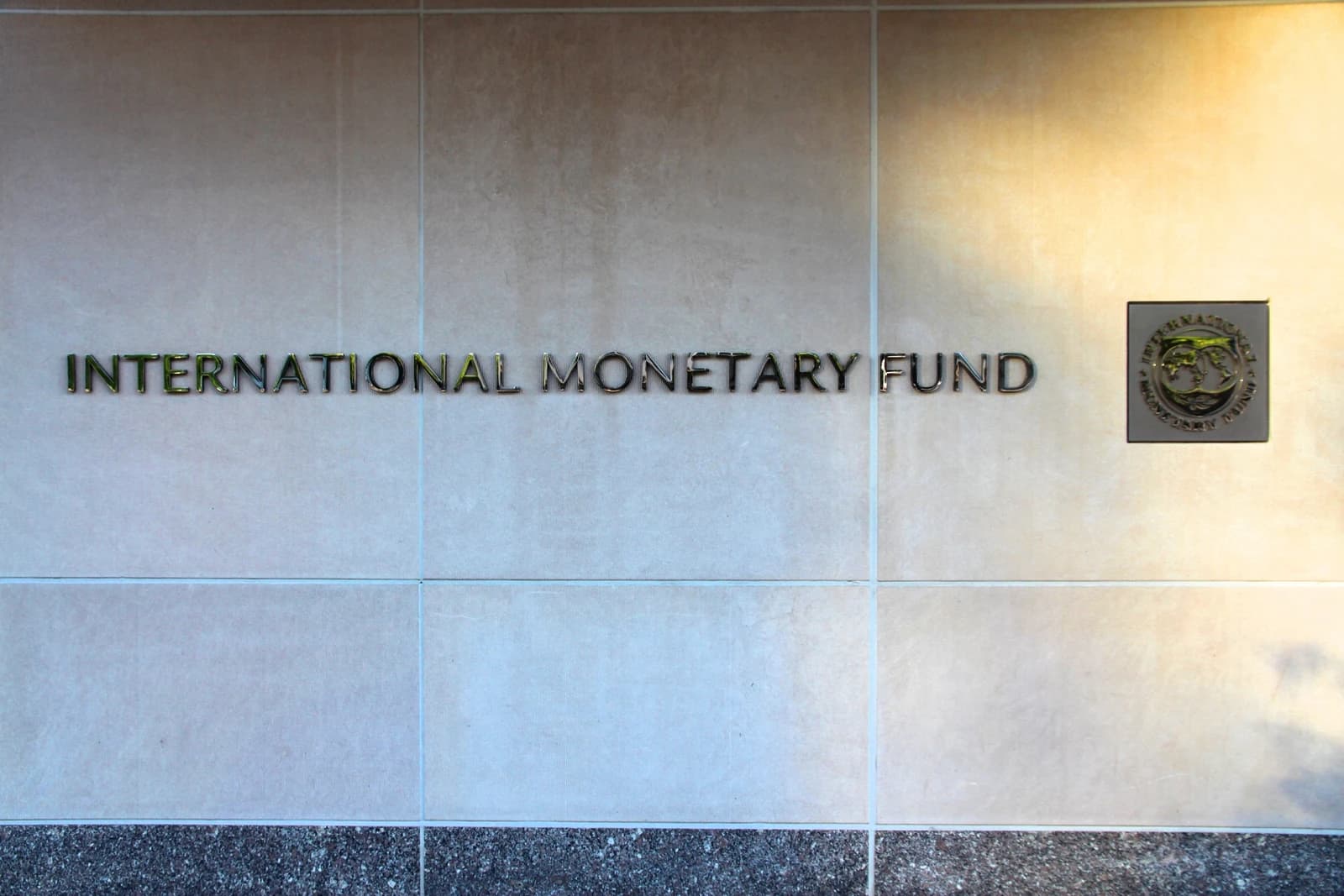 The name "INTERNATIONAL MONETARY FUND" in metallic letters on a building facade.